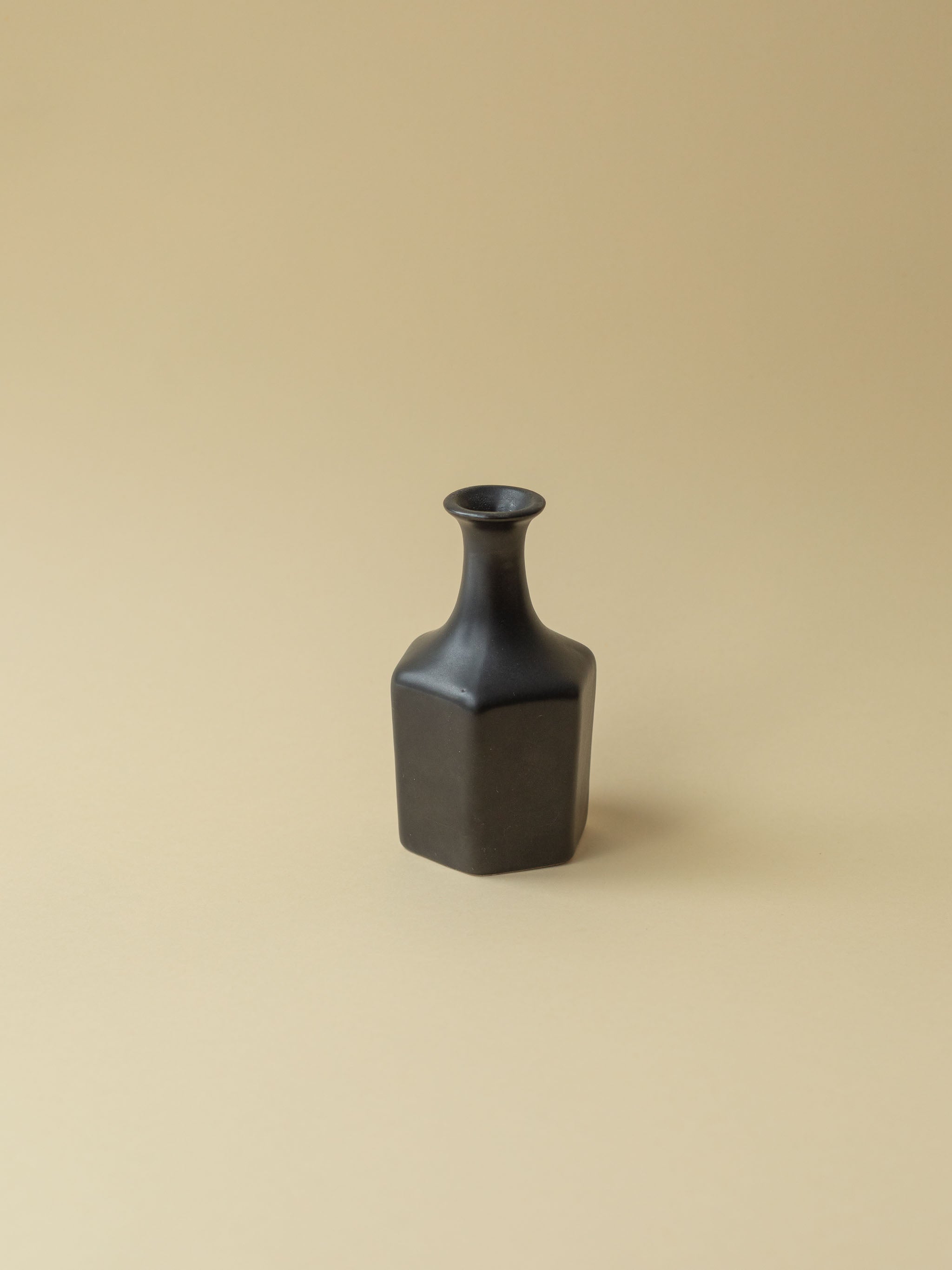 A black Kupittaan Savi vintage ceramic vase in bottle shape. A view from the side, back side. Scandinavian design from Finland.