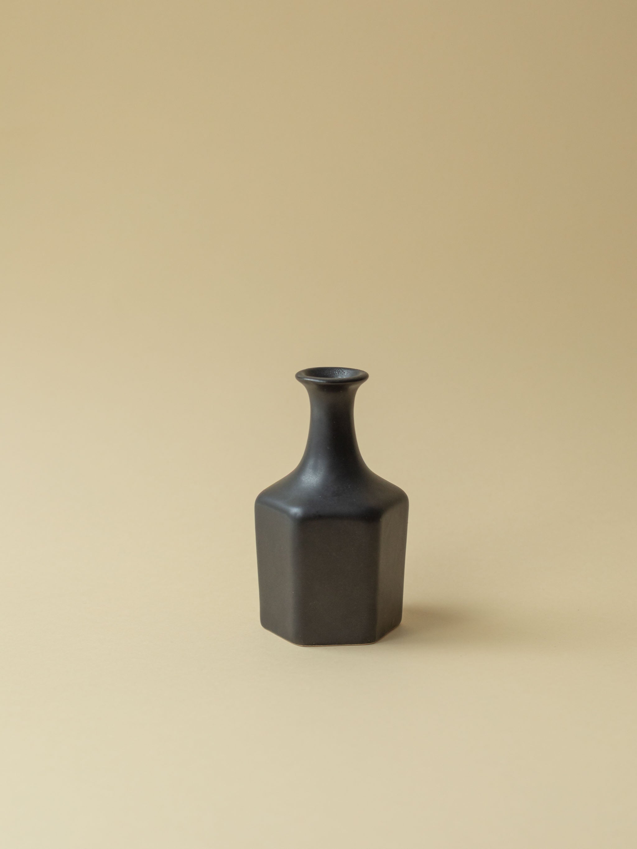 A black Kupittaan Savi vintage ceramic vase in bottle shape. Front view. Scandinavian design from Finland.