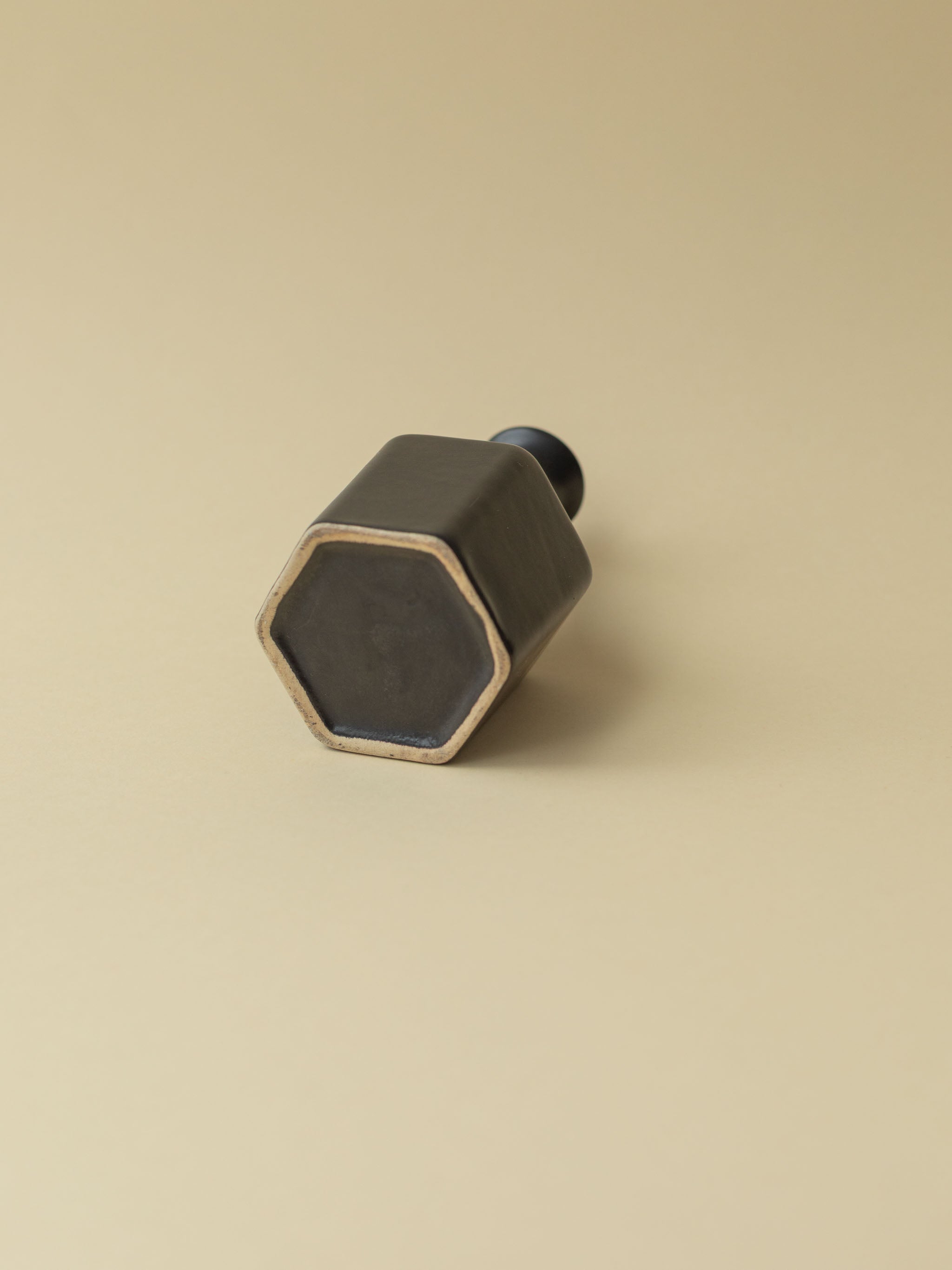 A black Kupittaan Savi vintage ceramic vase in bottle shape. Bottom view. Scandinavian design from Finland.