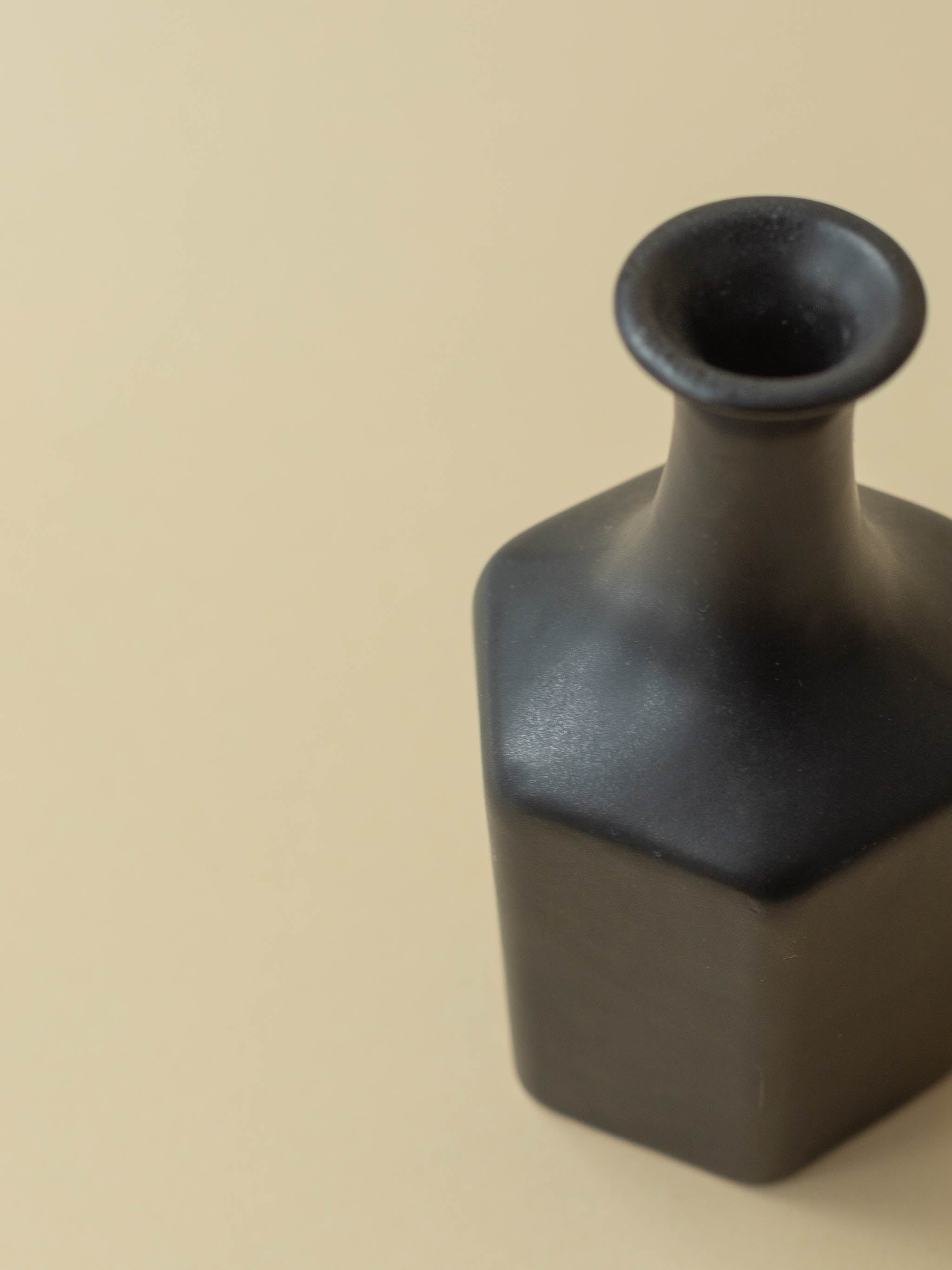 A black Kupittaan Savi vintage ceramic vase in bottle shape. A view from top down. Scandinavian design from Finland.