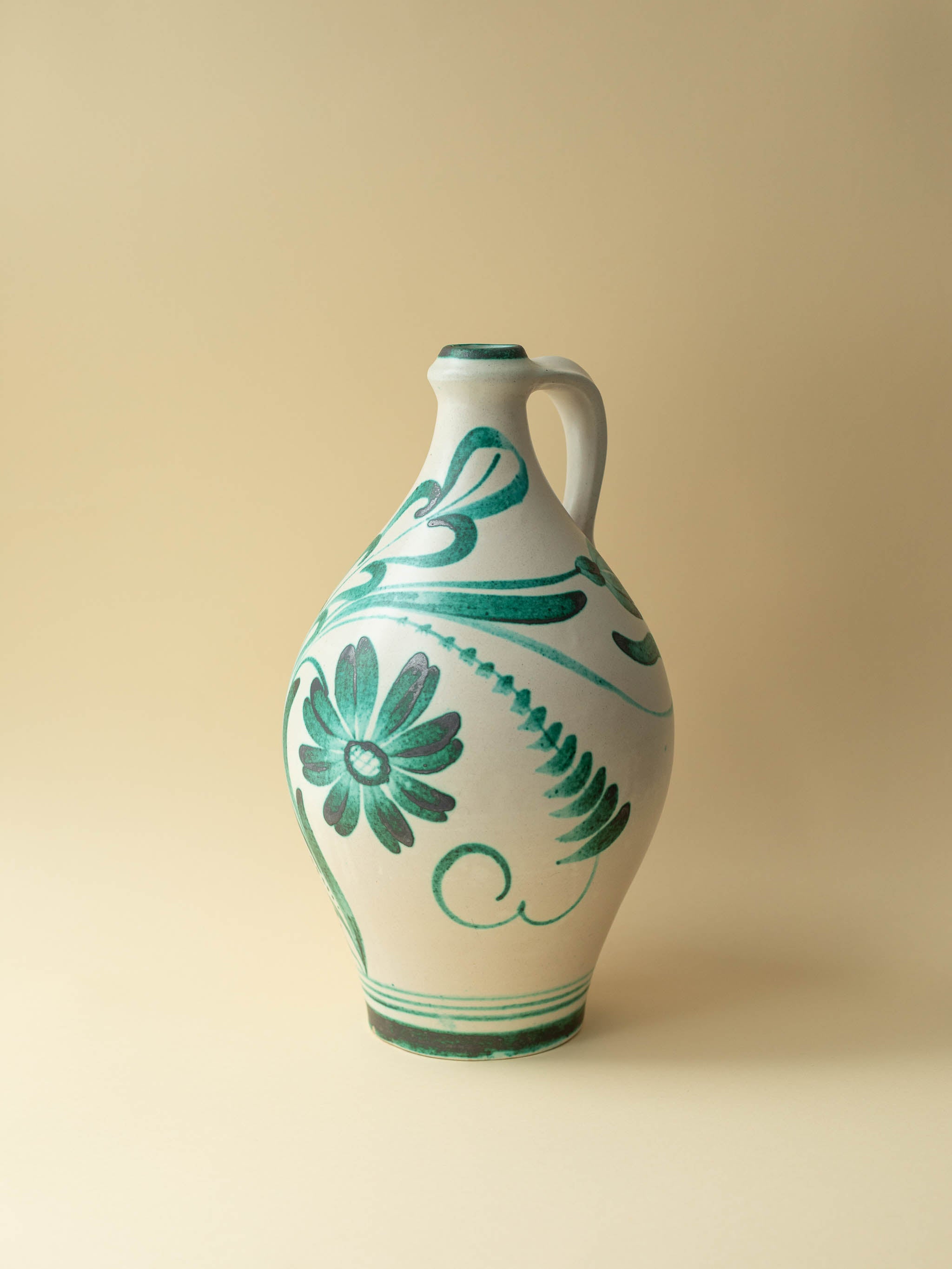 A crean coloured vintage ceramic vase by Kupittaan Savi with a hand painted floral motif in green by Tapio Kinnunen. Scandinavian design from Finland. A view from the front.