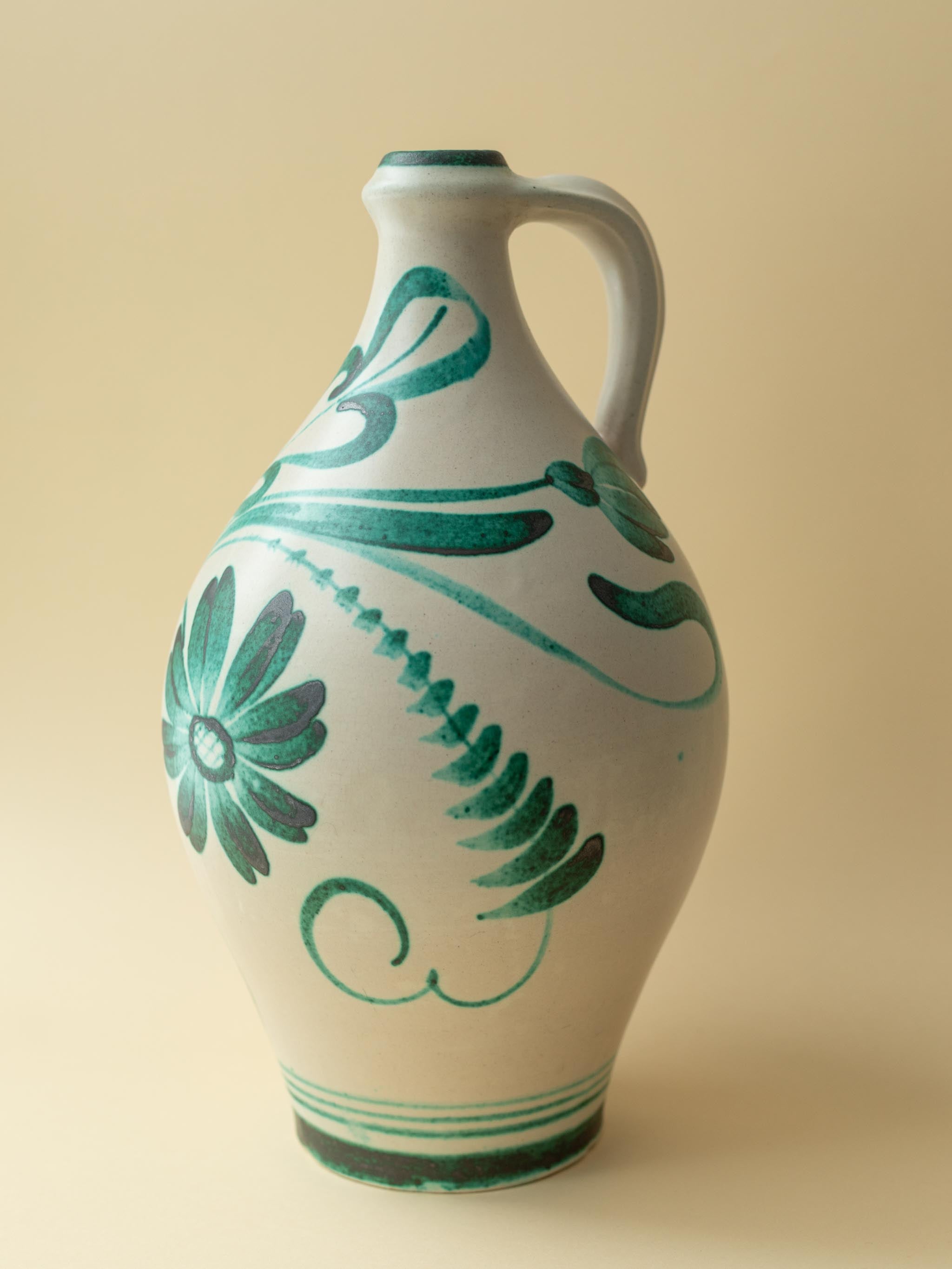 A crean coloured vintage ceramic vase by Kupittaan Savi with a handpainted floral motif in green. Scandinavian design from Finland. A closer up view from side.
