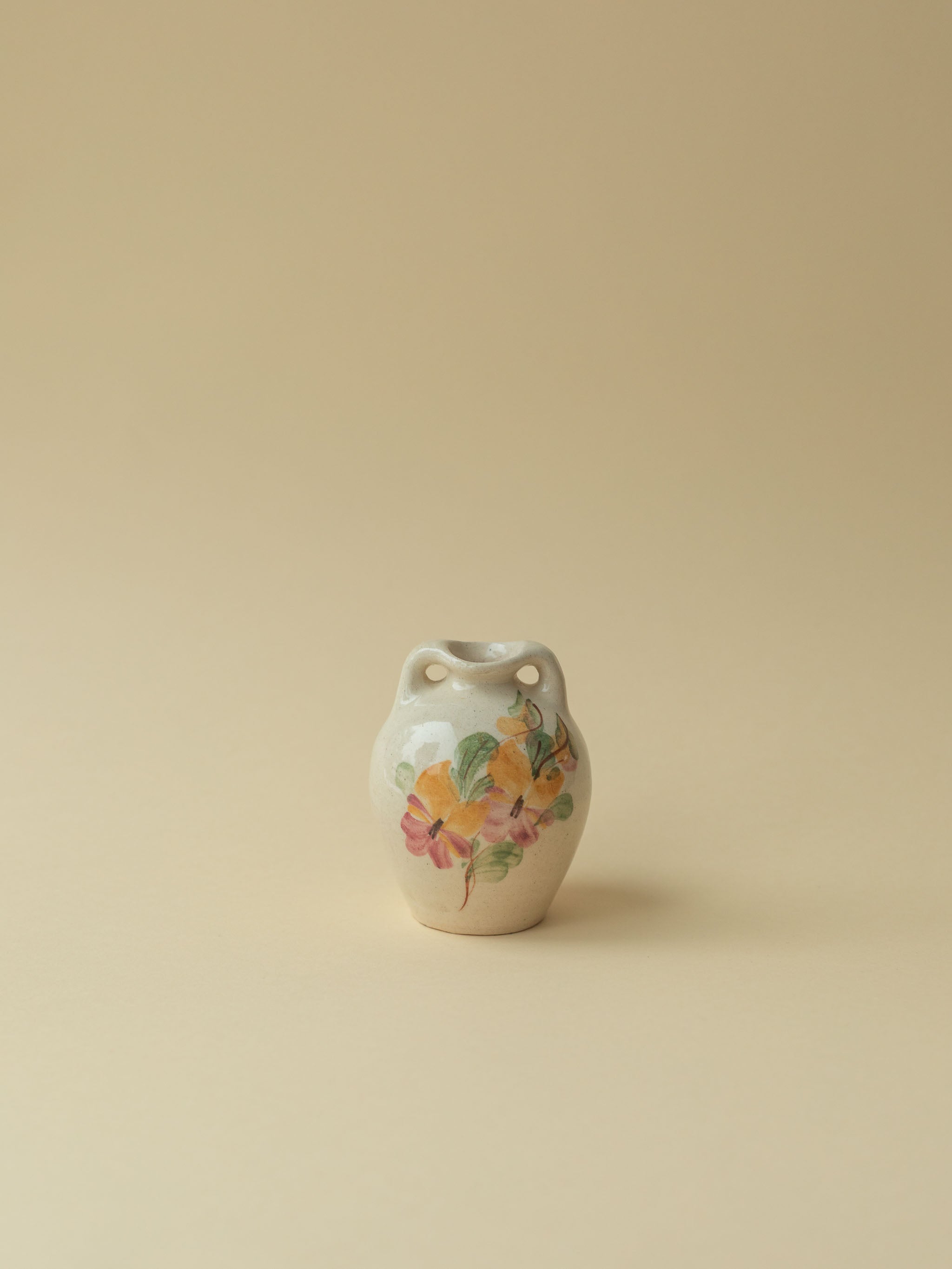 A miniature Kupittaan Savi vintage ceramic vase in amphora form.  Hand painted floral motif. A view from the front side. Scandinavian design from Finland.