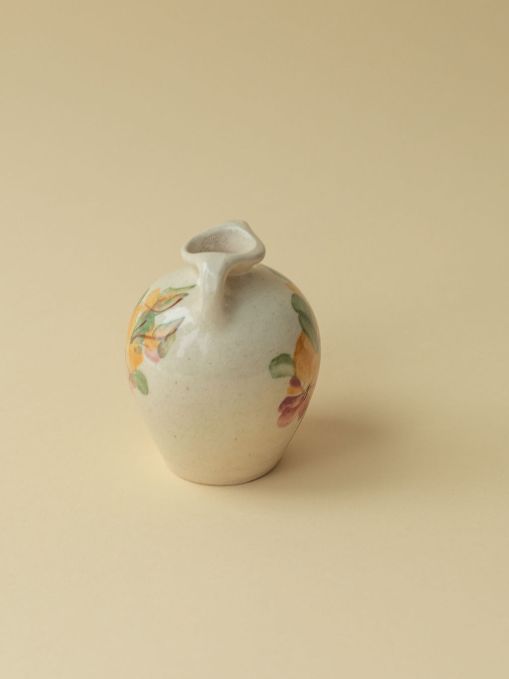 A miniature Kupittaan Savi vintage ceramic vase in amphora form.  Hand painted floral motif. A view from the side. Scandinavian design from Finland.
