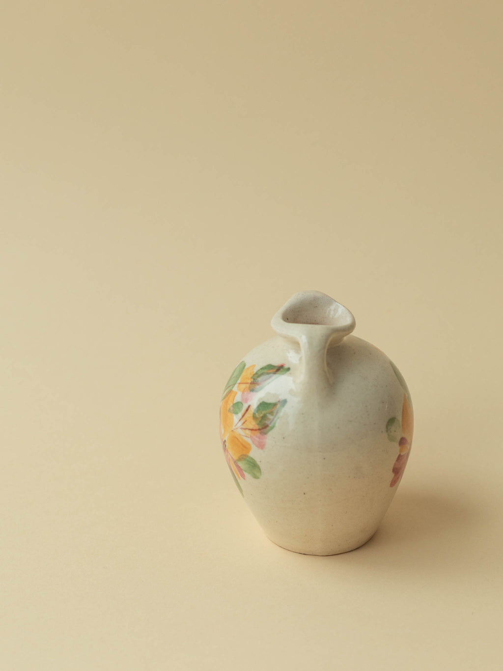 A miniature Kupittaan Savi vintage ceramic vase in amphora form.  Hand painted floral motif. A view from the side. Scandinavian design from Finland.