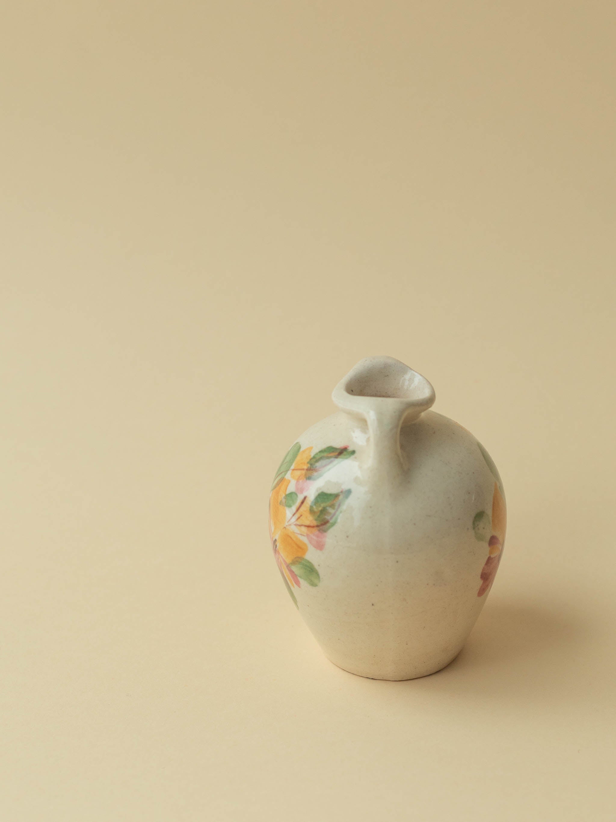 A miniature Kupittaan Savi vintage ceramic vase in amphora form.  Hand painted floral motif. A view from the side. Scandinavian design from Finland.