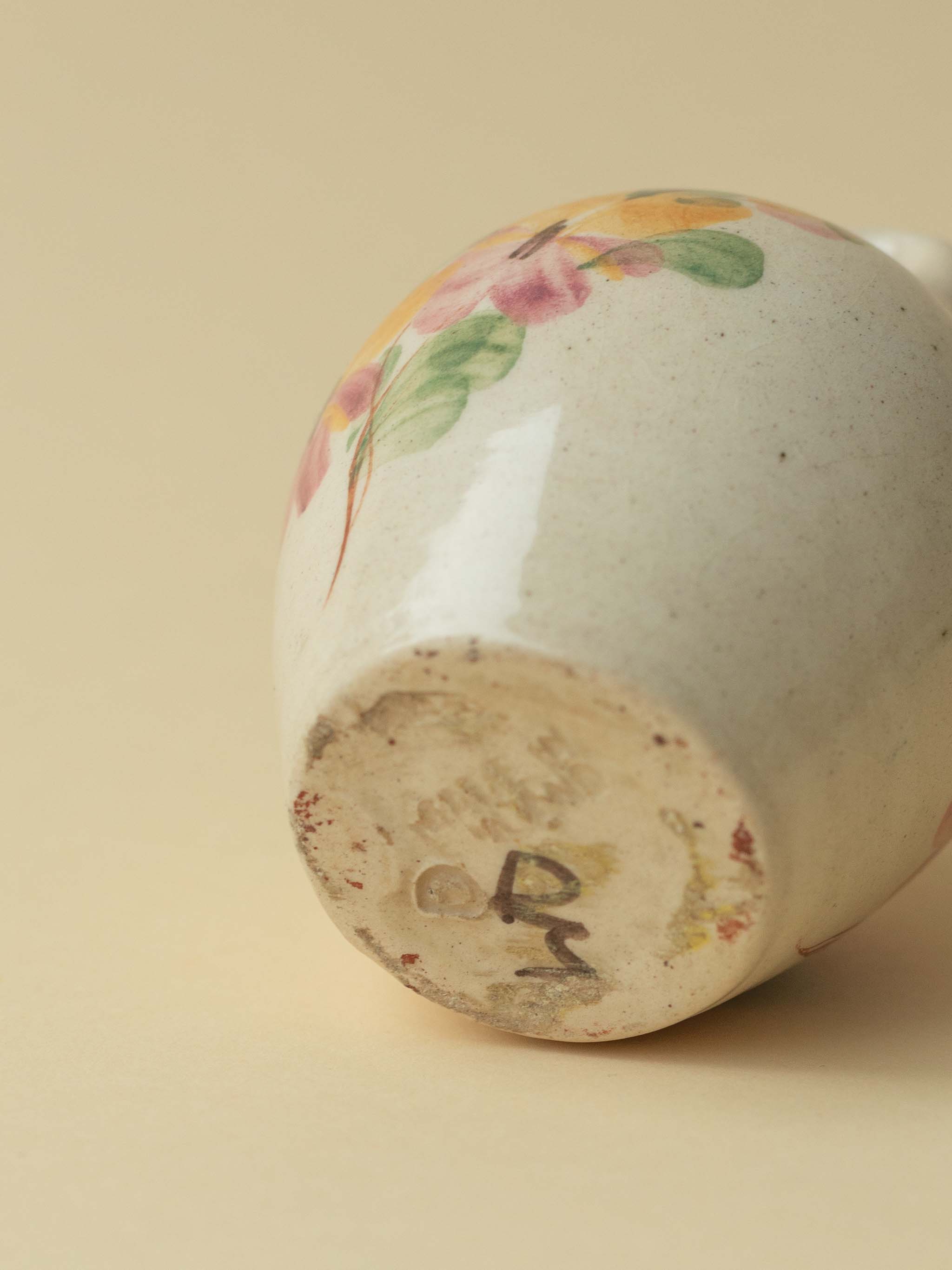A miniature Kupittaan Savi vintage ceramic vase in amphora form.  Hand painted floral motif. A view of the bottom showing signature and stamp. Scandinavian design from Finland.