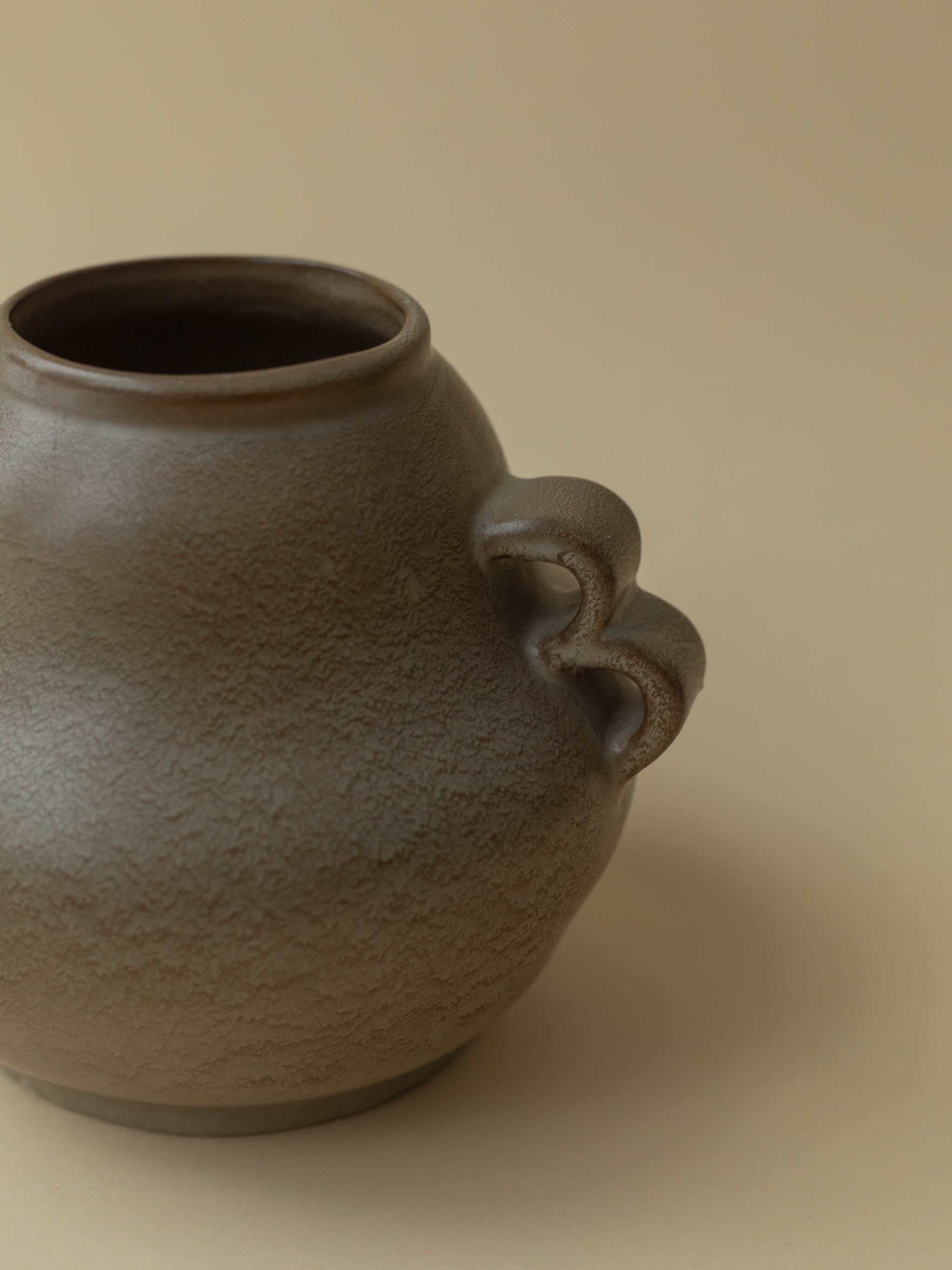 A brown vintage ceramic vase by Kupittaan Savi. Scandinavian design from Finland. A close up view showing the handle.