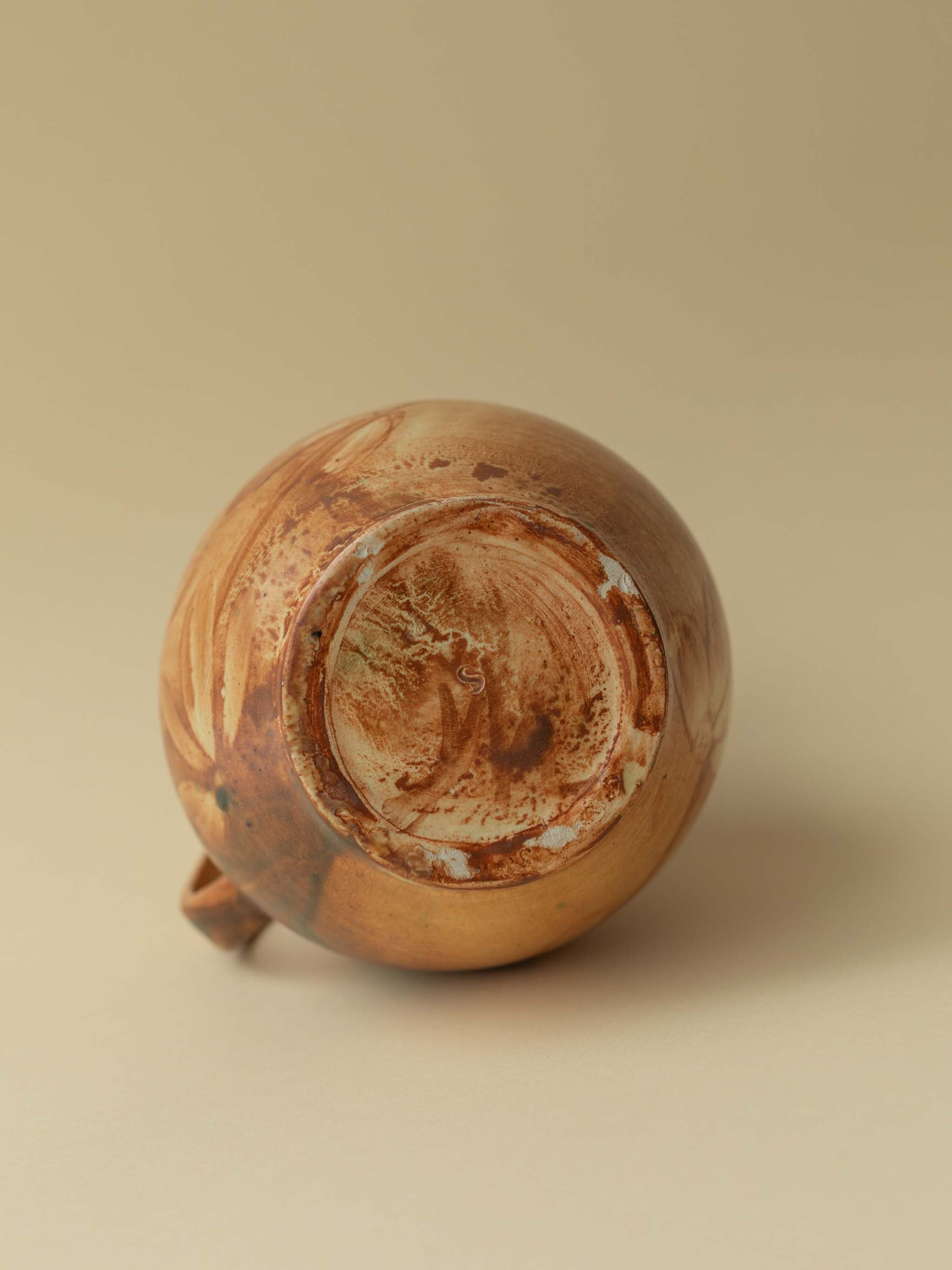 A brown toned vintage ceramic vase by Kupittaan Savi in jug or pitcher form. Scandinavian design from Finland. A view straight from the back showing the signature at the bottom.
