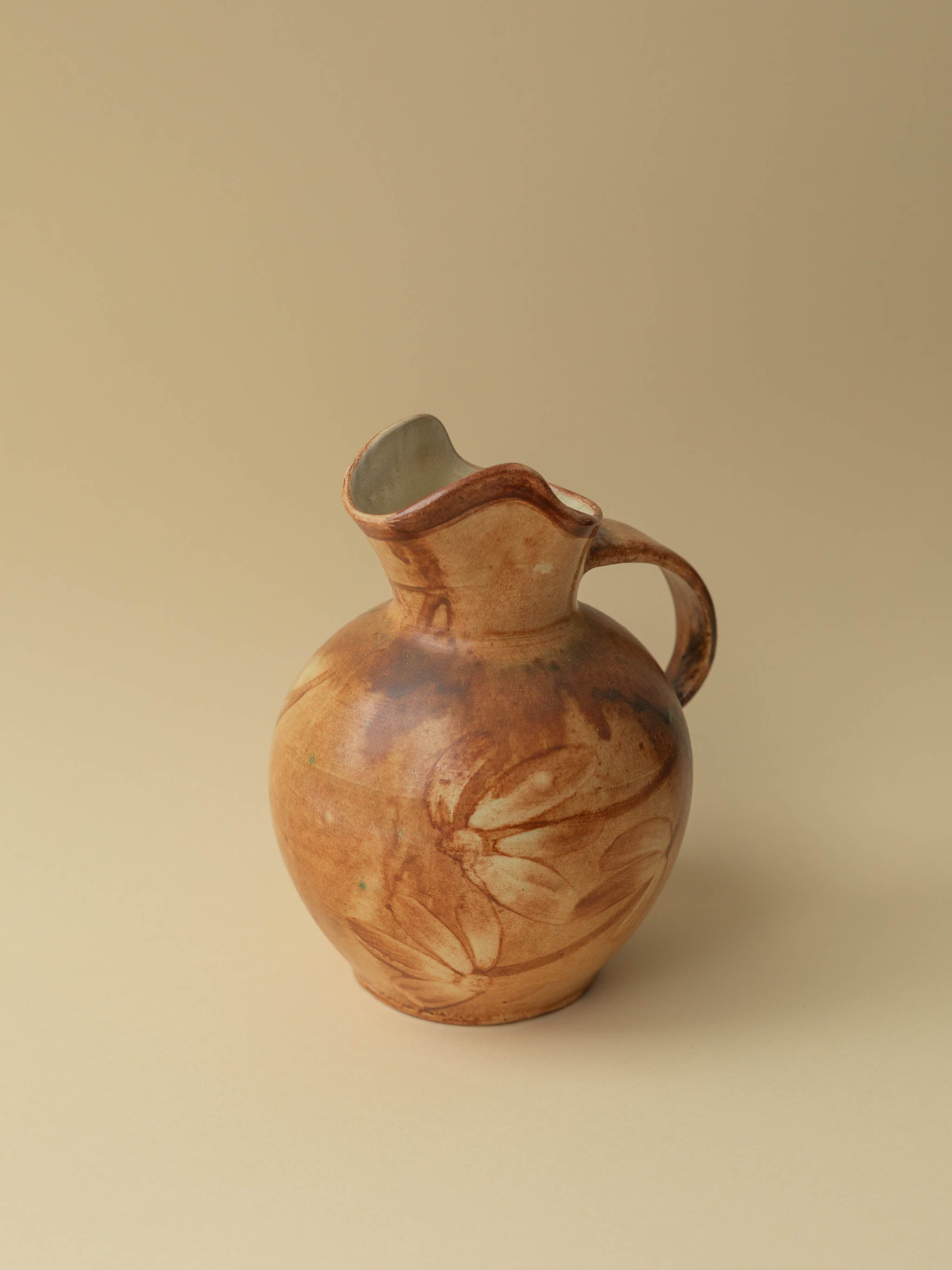 A brown toned vintage ceramic vase by Kupittaan Savi in jug or pitcher form. Scandinavian design from Finland. A view from the side showing the floral painted motif.