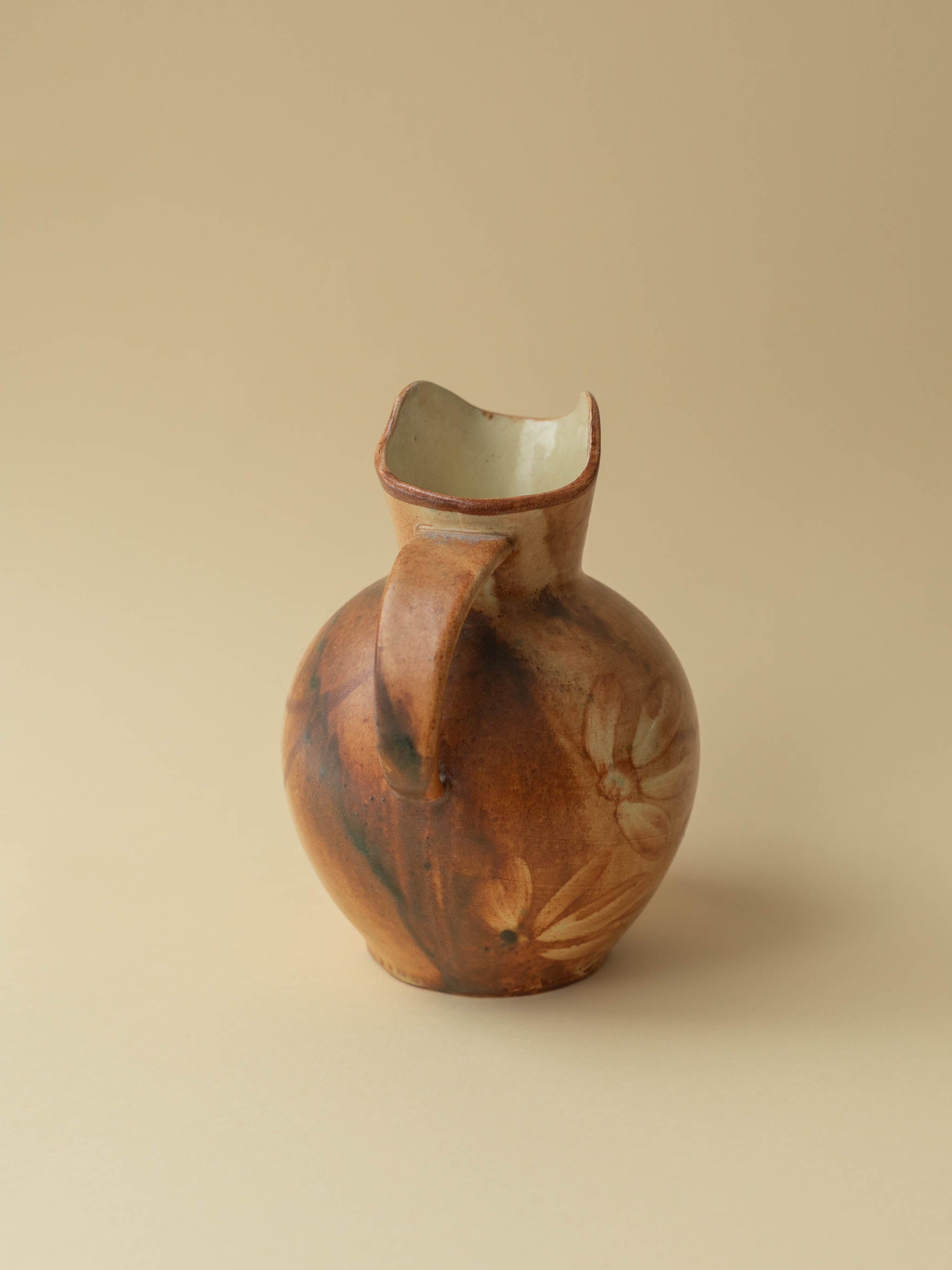 A brown toned vintage ceramic vase by Kupittaan Savi in jug or pitcher form. Scandinavian design from Finland. A view from the back side.