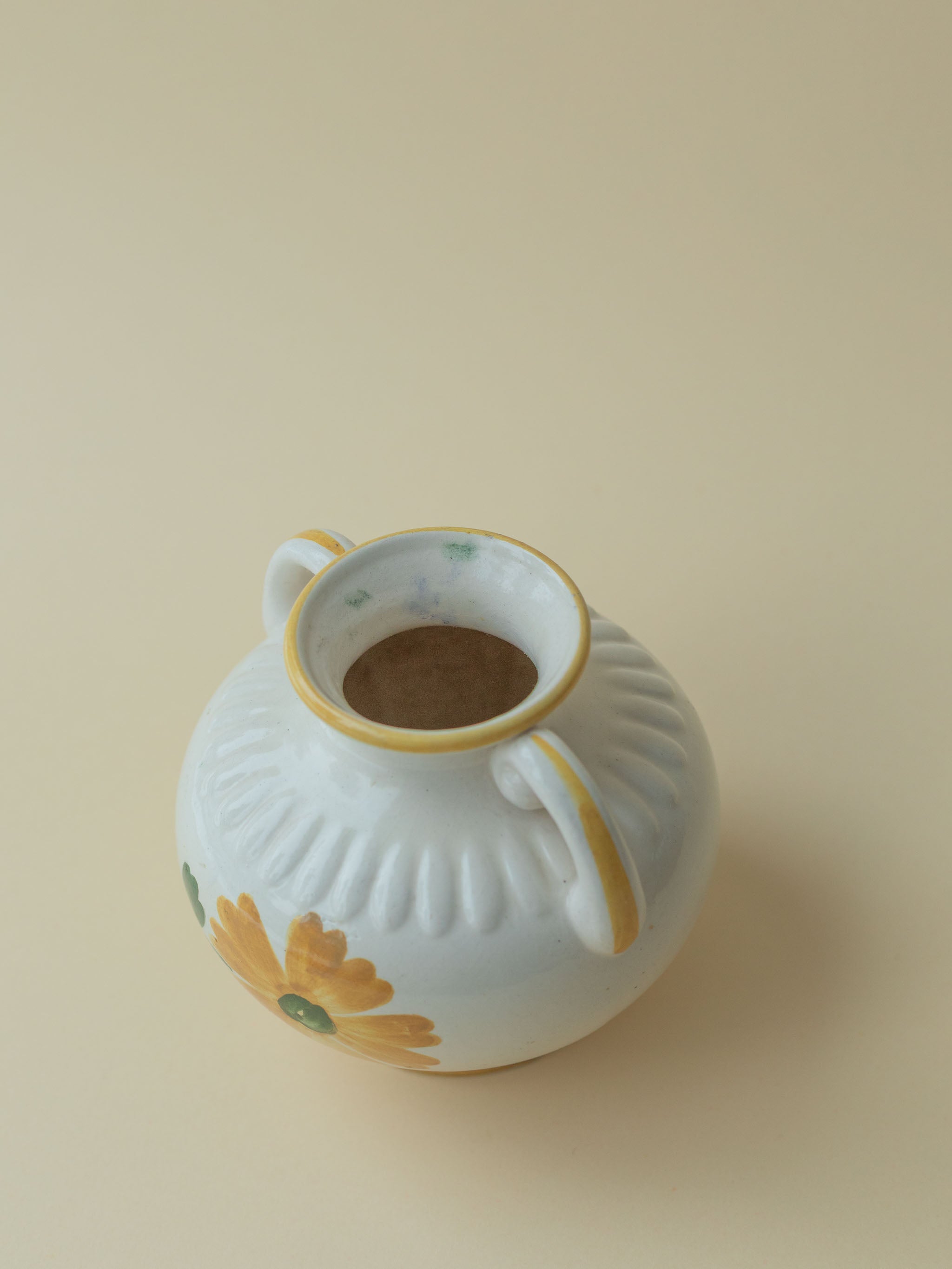 A white vintage ceramic vase by Kupittaan Savi with a handpainted floral motif in green and yellow. Scandinavian design from Finland. A view from the top.