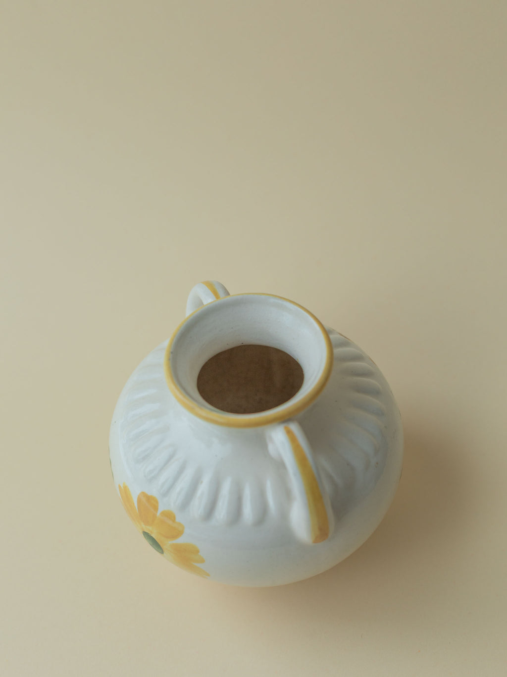 A white vintage ceramic vase by Kupittaan Savi with a handpainted floral motif in green and yellow. Scandinavian design from Finland. A view from the top.