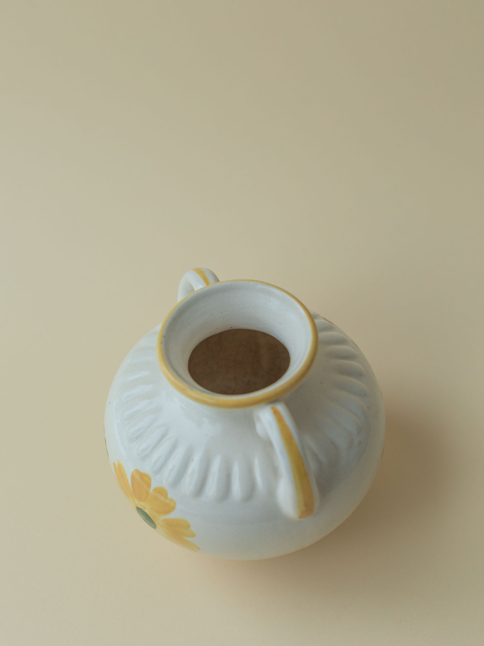 A white vintage ceramic vase by Kupittaan Savi with a handpainted floral motif in green and yellow. Scandinavian design from Finland. A view from the top.
